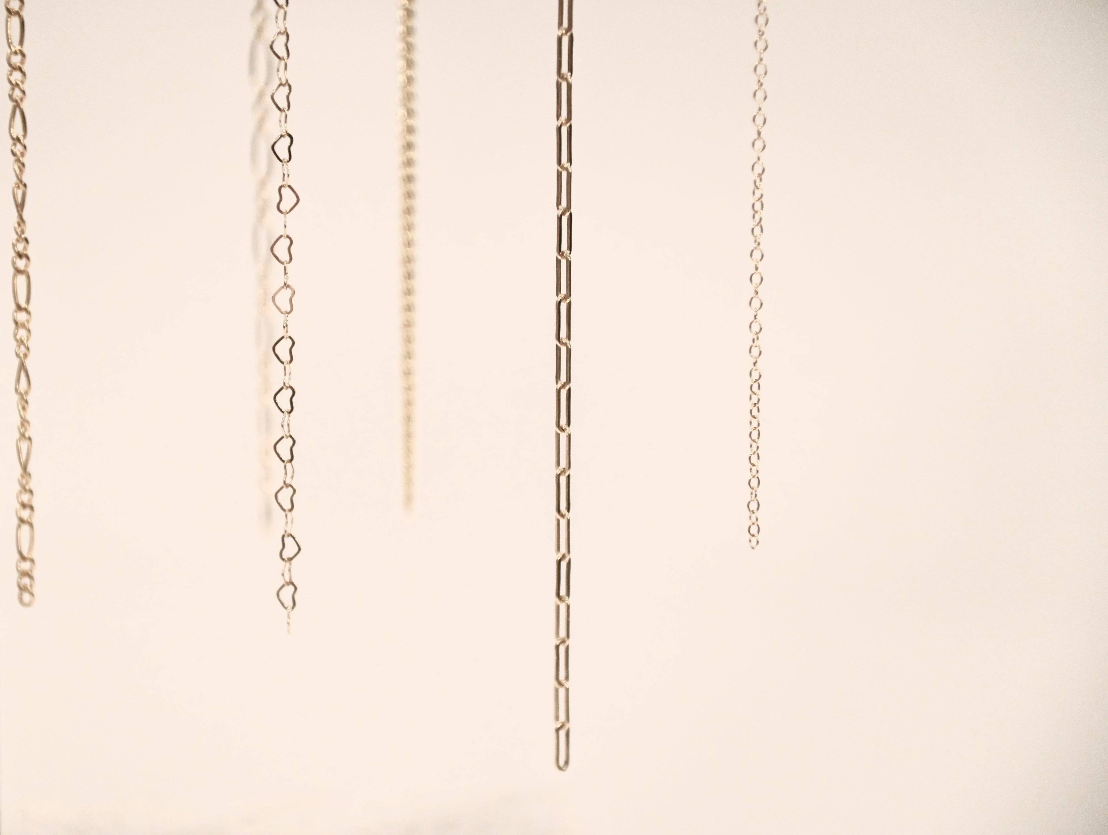 Two silver necklaces on a light beige background